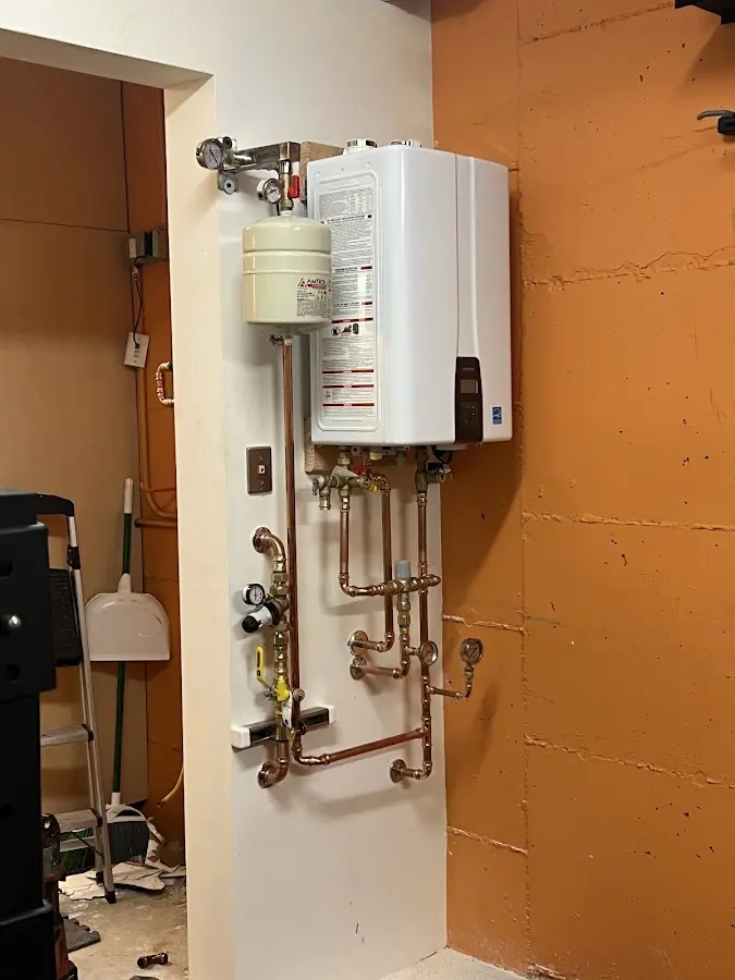 Plumbing technician inspecting water heater connections in Neenah